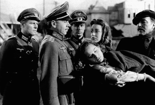 Screenshot from the film "None Shall Escape" showing German officers, a man and a woman standing around a body of a young woman.