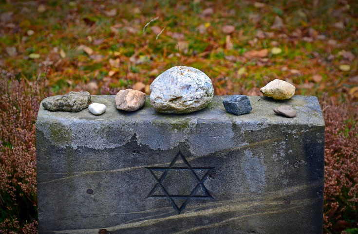 Several stones sitting on top of a grave marked with a Star of David