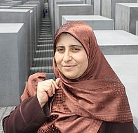 A woman wearing a hijab and standing in front of the Holocaust Memorial in Berlin.