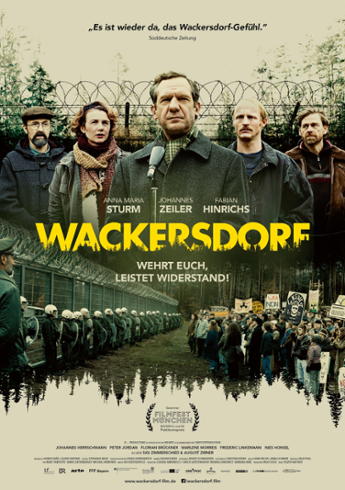 Movie poster for film Wackersdorf. On the top half, five people stand behind a microphone and in front of a barbed wire fence. On the bottom half, a group of anti-nuclear activists stand opposite police in riot gear. Text reads: "Es ist wieder da, das Wackersdorf-Gefuhl." Wackersdorf, Wehrt Euch, Leistet Widerstand. Actors: Anna Maria Sturm, Johannes Zeiler, Fabian Hinrichs.