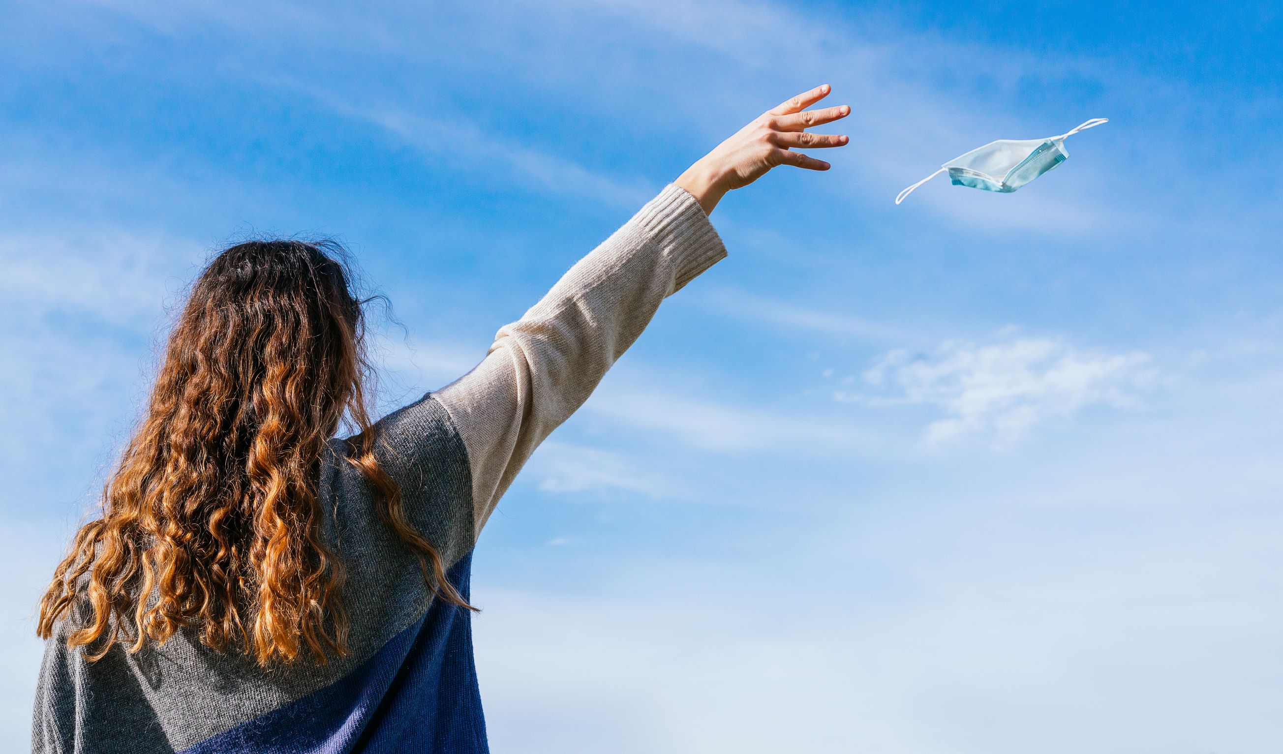 woman letting face mask fly into the sky