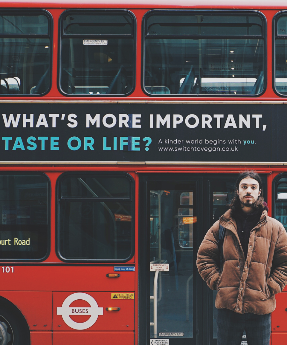 Ed Winters standing in front of bus with ad reading "What's more important, taste or life?"