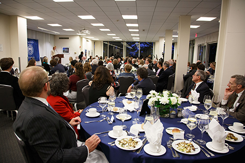 A long view of the festive gala dinner with people seated at banquet tables and Ambassador Haber speaking from the podium
