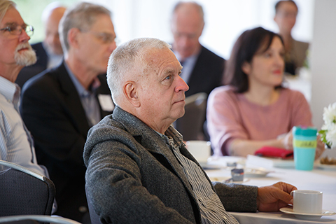 A view of people seated at tables listening to the presentation