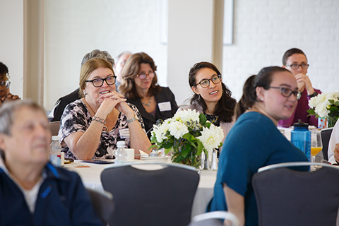 Audience seated at tables listening to the panel discussion, including Heidi McAllister, panelist Tamar Forman-Gejrot ’16 and Theresa Weis '20 on the right.