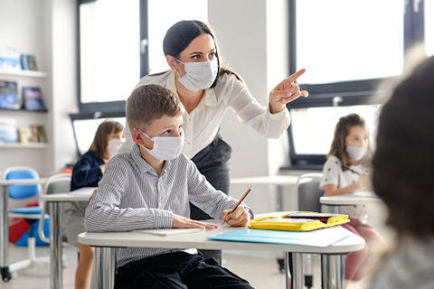 Teacher pointing for a student both with masks