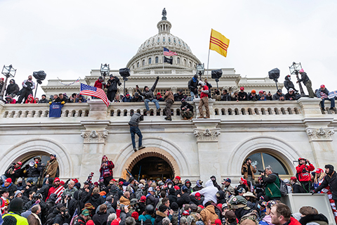 Picture of the insurrection with people in front of the Capitol building