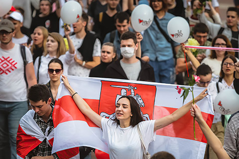 Woman holding the flag of Belarus in a crowd