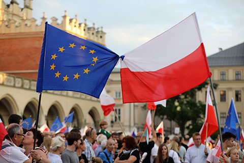 EU flag and Polish flag next to each other in a crowd outdoors