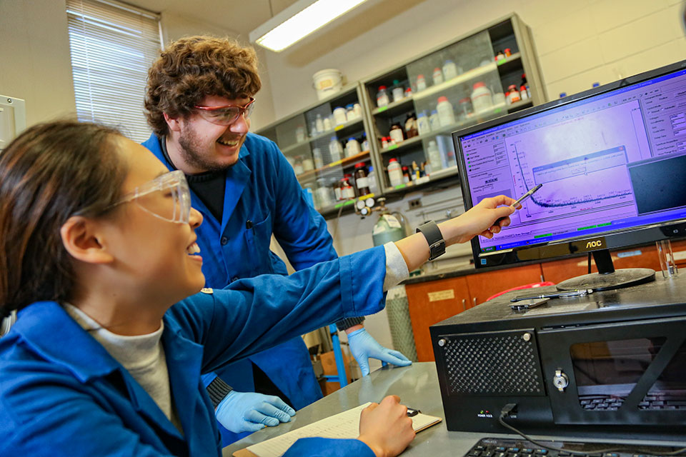 Professor Isaac Krauss works with three students in the lab