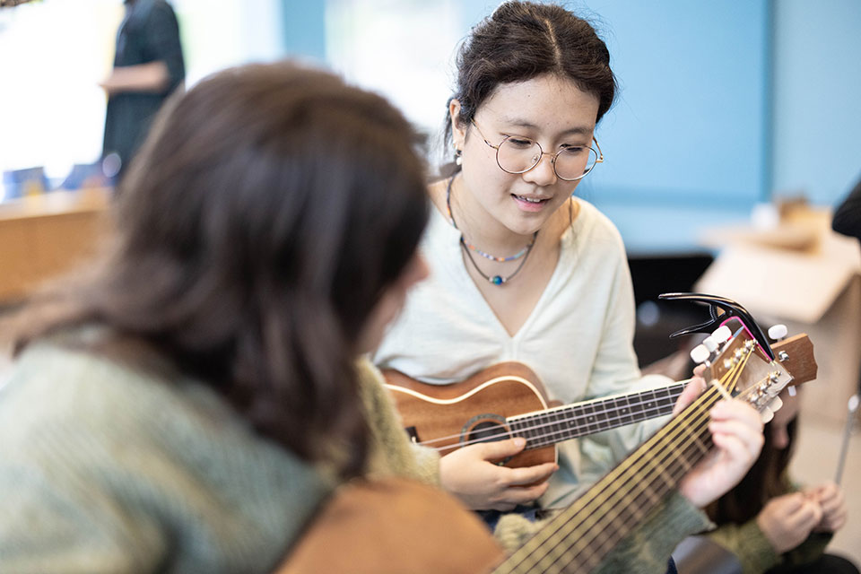 Two students play the guitar together in guitar club.