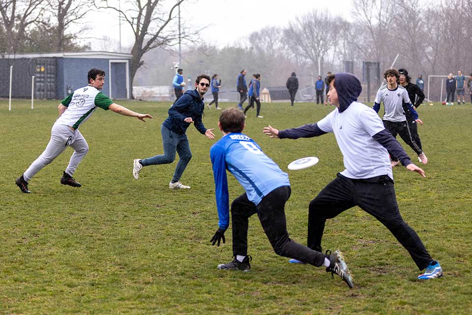 The men's ultimate frisbee team plays frisbee outside.