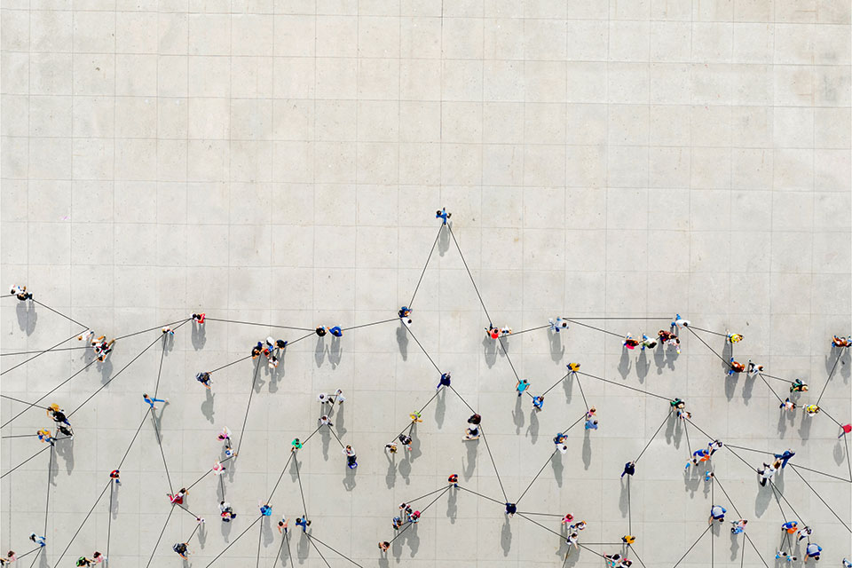 Crowd from above forming a growth graph with lines connecting between them to show how COVID-19 can expand. Photo Credit: istockphoto.com/Orbon Alija