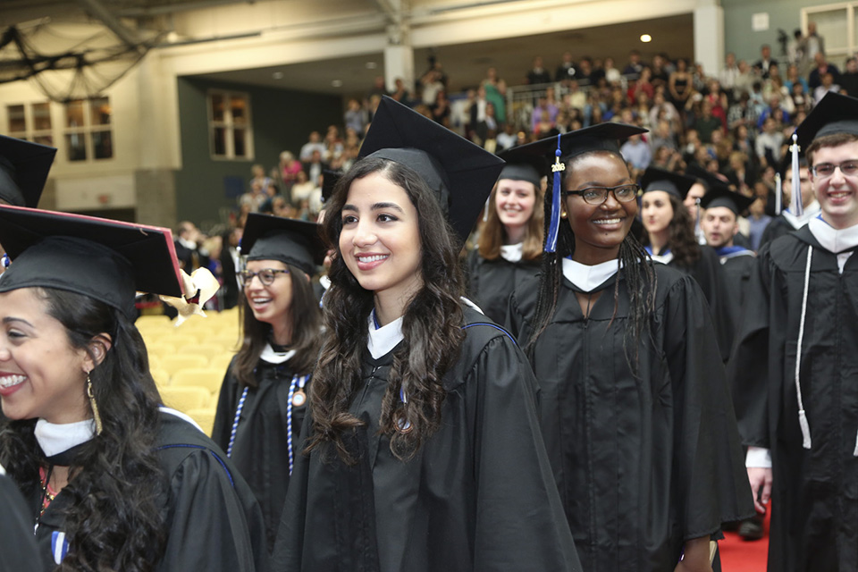 The Class of 2016 processes down the red carpet, with big smiles, some smiling at onlookers.