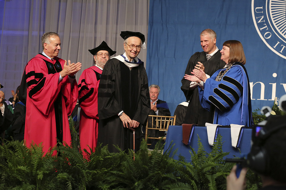 An honorary degree is conferred upon Frank Brandeis Gilbert, grandson of the university's namesake. The Provost and other dignitaries on the state applaud.