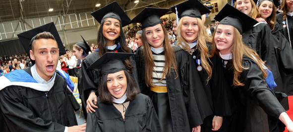 Male and female students smiling, wearing caps and gowns