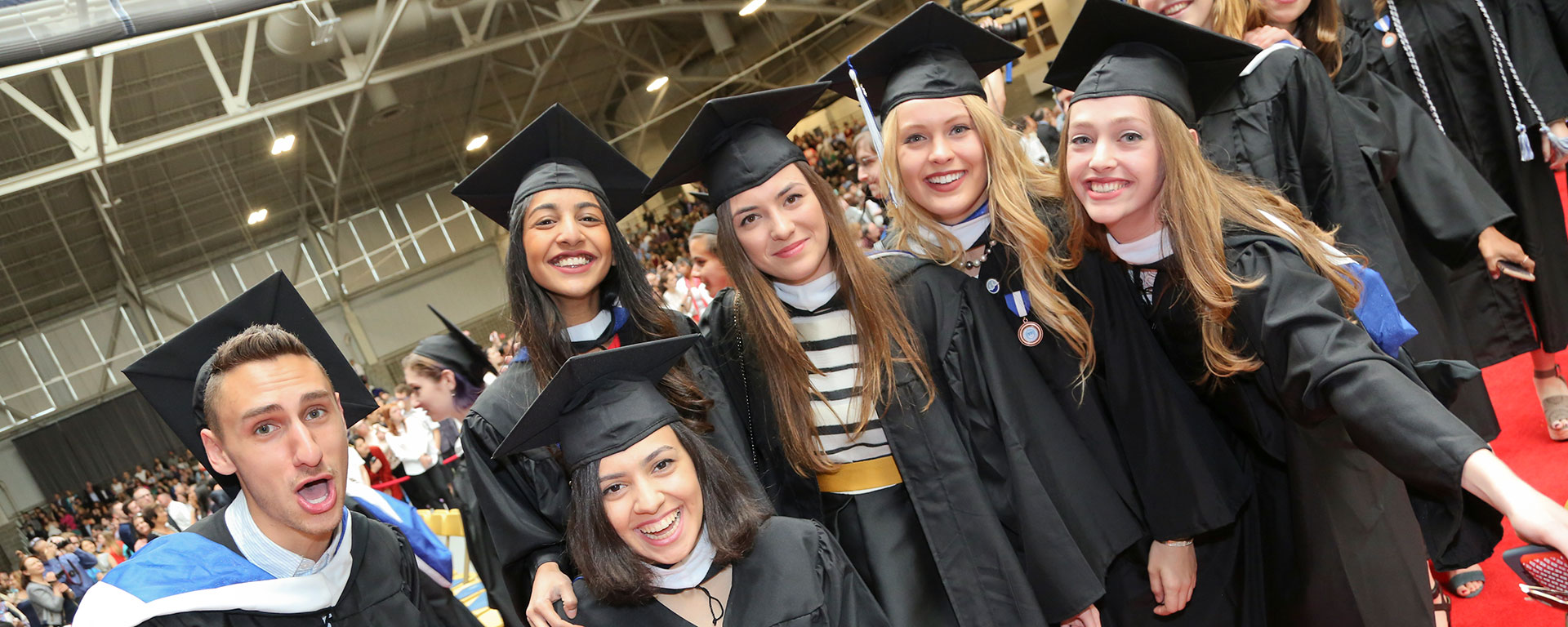Students standing and smiling, wearing caps and gowns