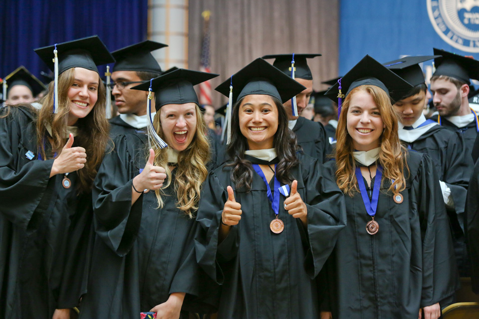 A group of graduates give thumbs up