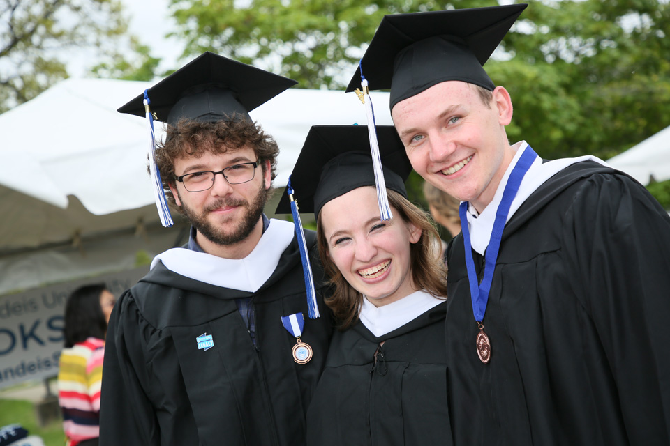 Three graduates smile at the camera