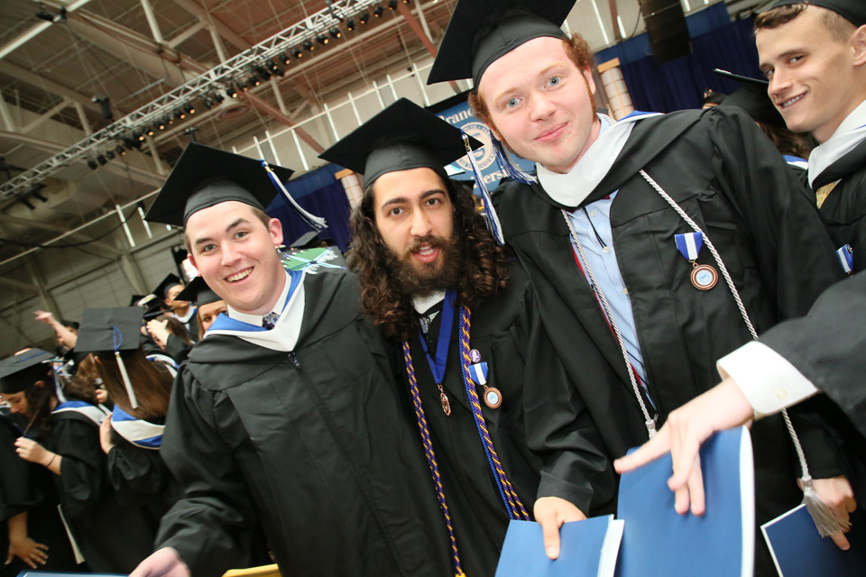 Three graduates smile at the camera