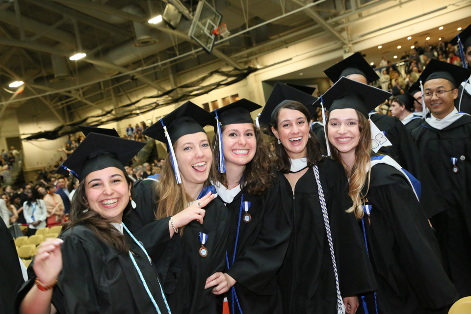 Students in caps and gowns energetically pose for the camera