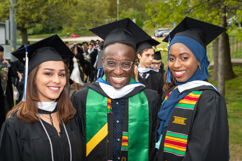 Three graduates pose outside