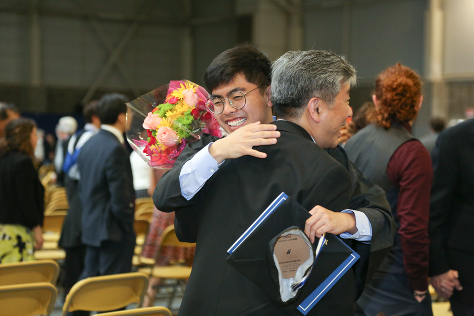 A graduate gets a hug from a family member