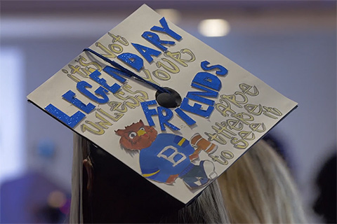 A graduation cap decorated with Ollie the Owl and words that read it's not legendary unless your friends are there to see it