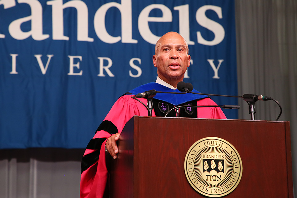 Deval Patrick standing behind a podium with the Brandeis seal