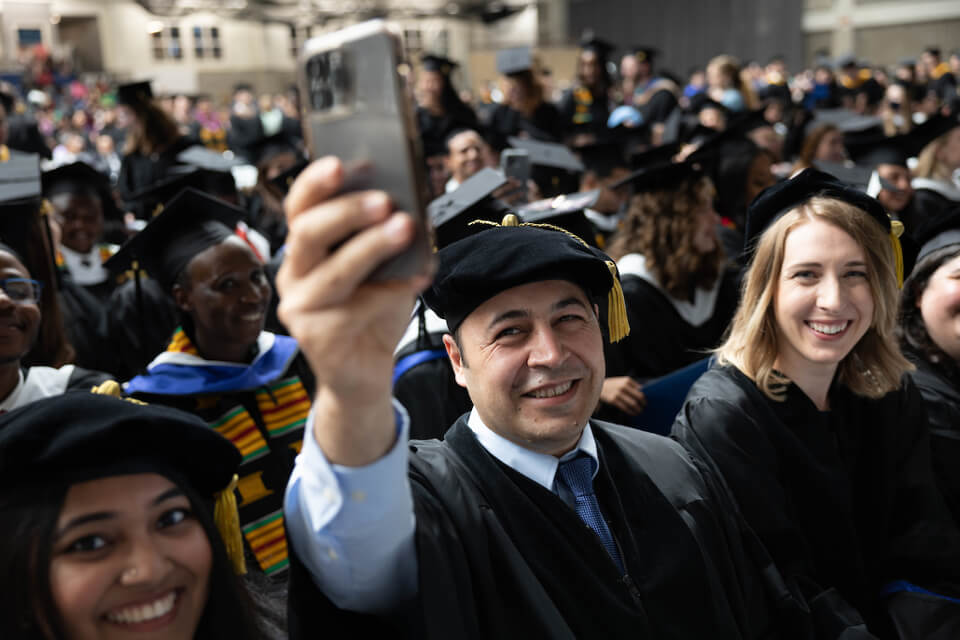 Hadi Kahalzadeh, Heller PhD’23, takes a selfie with fellow graduates.