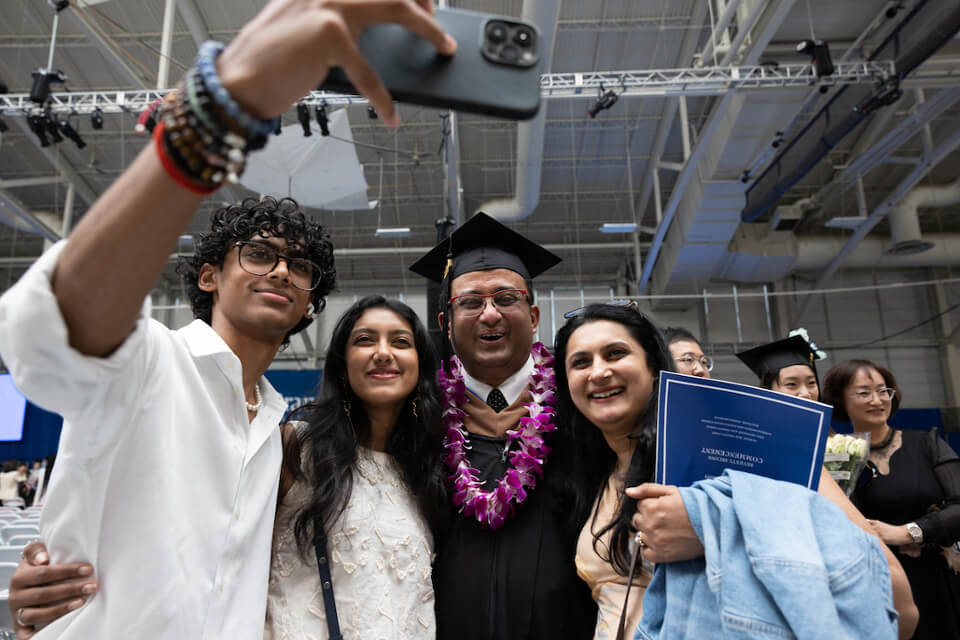 From left to right, Keshav Krishna, Paru Nair, Dr. Satya Krishna Ramachandran, Heller MBA '23, Priya Nair take a selfie  at the Gosman Sports and Convocation Center.