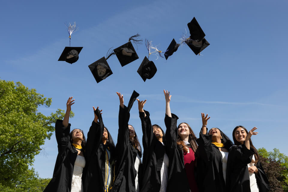 Students toss mortar boards in celebration.