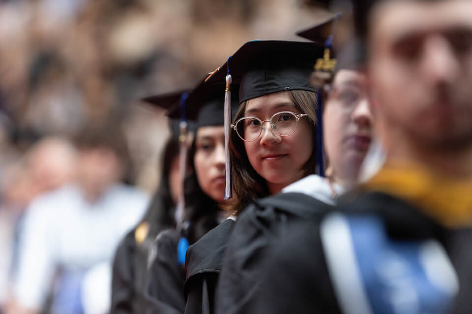 Students listen to Commencement speakers at the Gosman Sports and Convocation Center during Commencement.