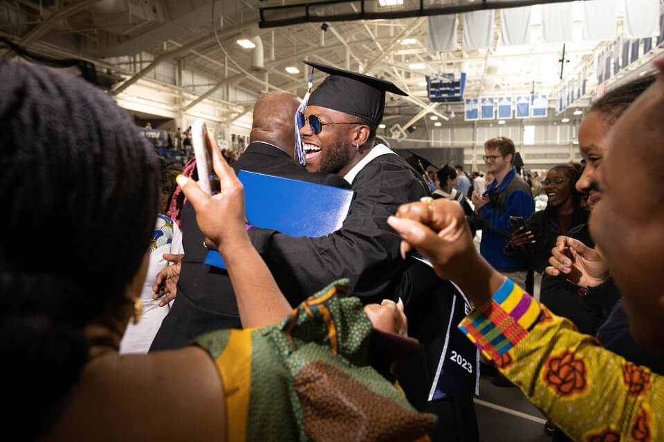 Terrell Brown dances as his family places fabric on the ground for him to walk upon, part of a ceremony rooted in their Liberian culture celebrating accomplishments of loved ones, after the undergraduate Commencement ceremony.