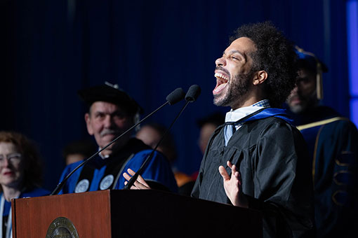 A graduate student sings the national anthem at Commencement.