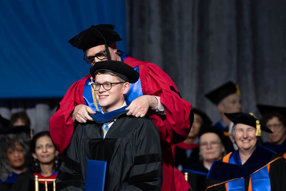 A graduate student is hooded during the Commencement ceremony