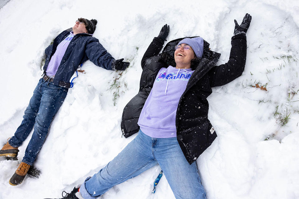 Students make snow angels in the snow.