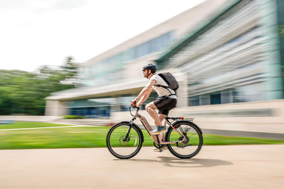 A student rides a bike on the Brandeis campus.