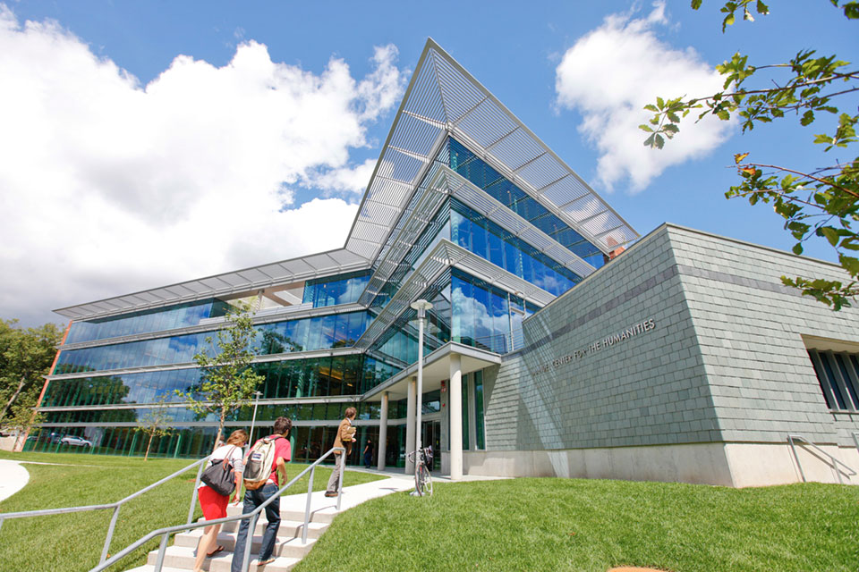 Students walk up the steps of the Mandel Center for the Humanities on a sunny day