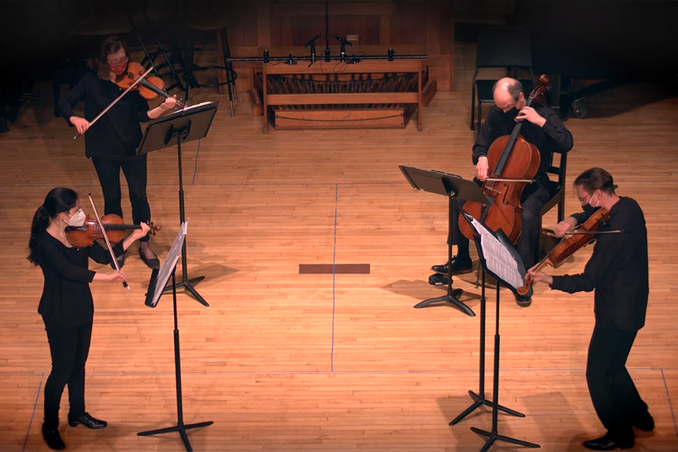 A screenshot of the Lydian String Quartet performing in masks on the Slosberg stage