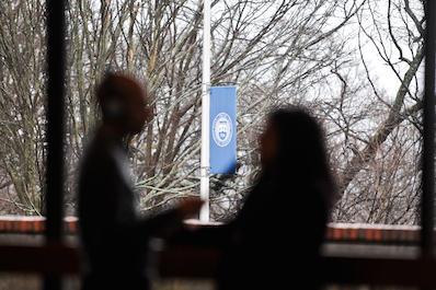 Silhouette of two people in front of window with with Brandeis banner in background