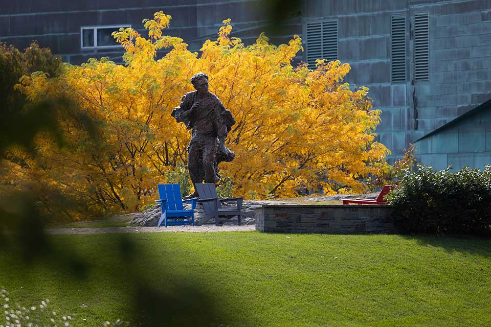 Statue of Louis Brandeis, a tree with vibrant yellow leaves in the background