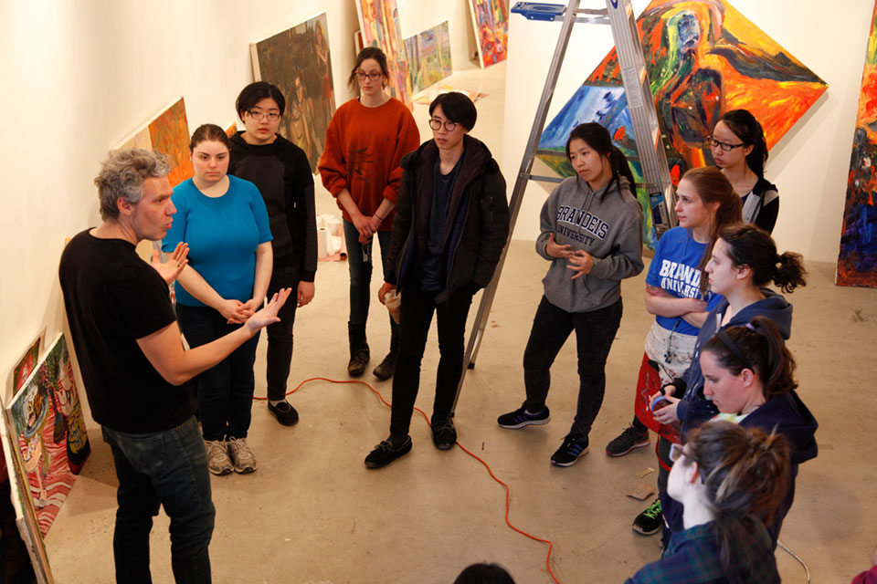 A professor talks with students in an art gallery