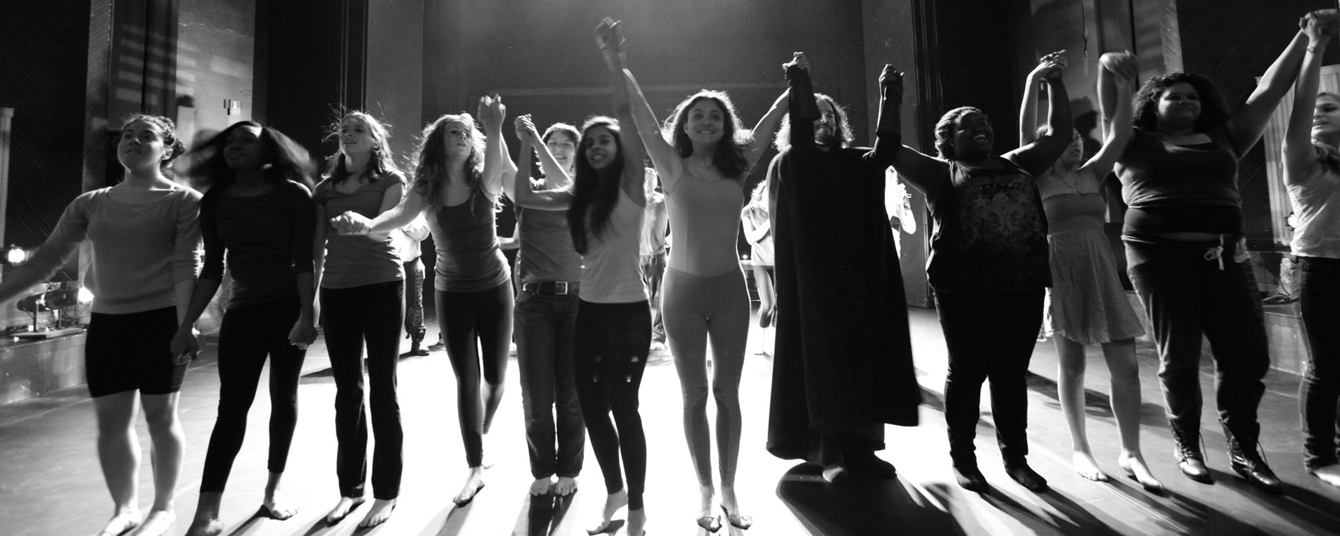 Students holding hands in line on a stage