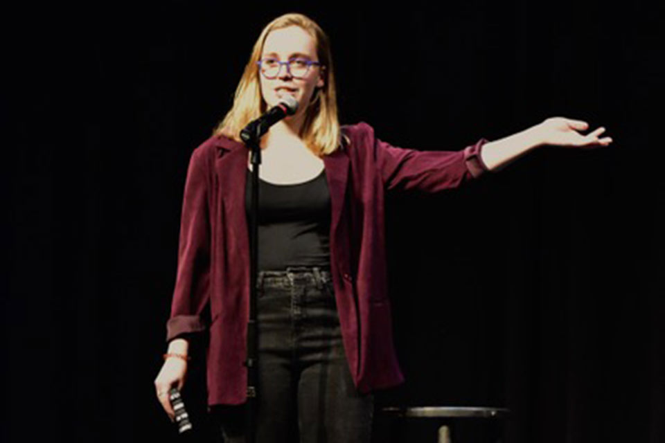 Anna standing at a mic onstage