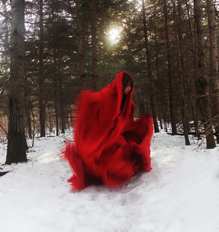 Jaime Black wearing a red dress in the forest in the snow