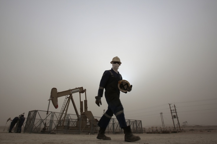 An oil worker walks by an oil pump during a sandstorm in the oil fields of Sakhir, Bahrain in January, 2015. 