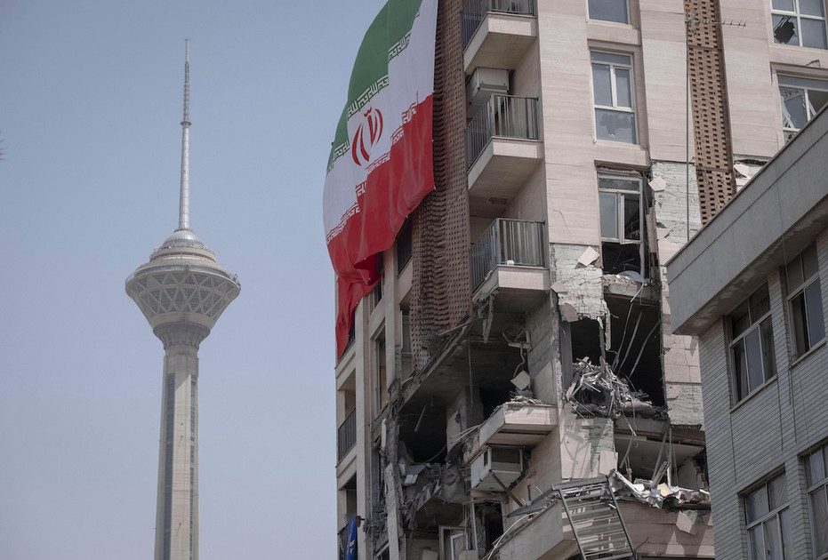An Iranian flag hangs from a building damaged by Israeli attacks in Tehran