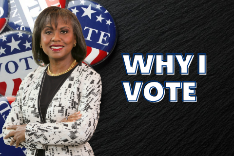 Anita Hill standing next to the words Why I Vote with VOTE buttons  in the background