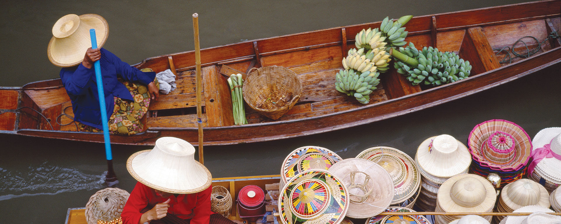 Two people in boats filled with produce and good